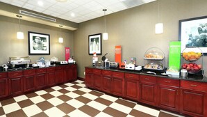 A breakfast bar with coffee machines, a fruit bowl, and a juice dispenser.
