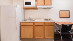 Eine kleine Küche mit Kühlschrank, Mikrowelle, Spüle und Holzschränken.
