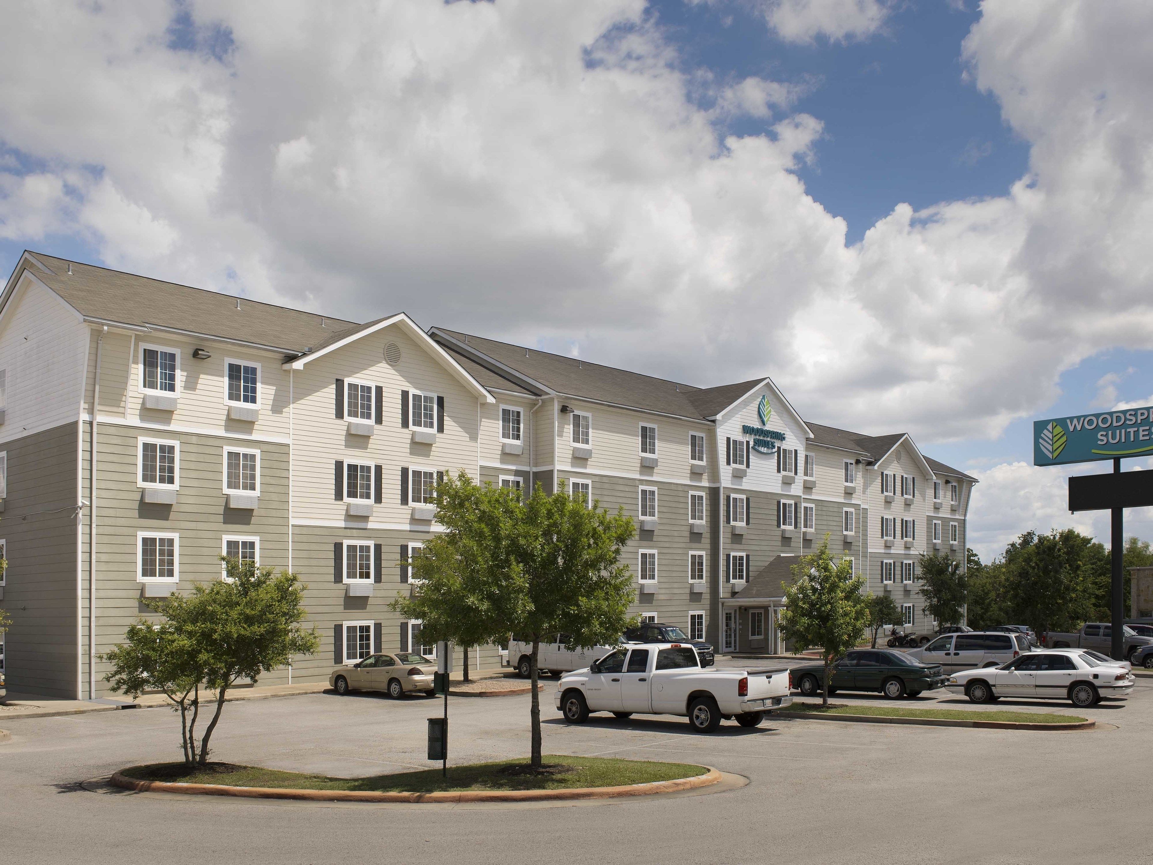 A multi-story hotel with a sign for Woodspree Suites.