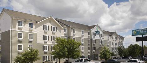 A multi-story hotel with a sign for Woodspree Suites.