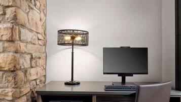 A desk with a computer monitor, keyboard, and a lamp.