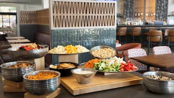 Un buffet proposant une variété d’aliments, notamment des noix, du fromage, du pop-corn, des légumes et des crackers.