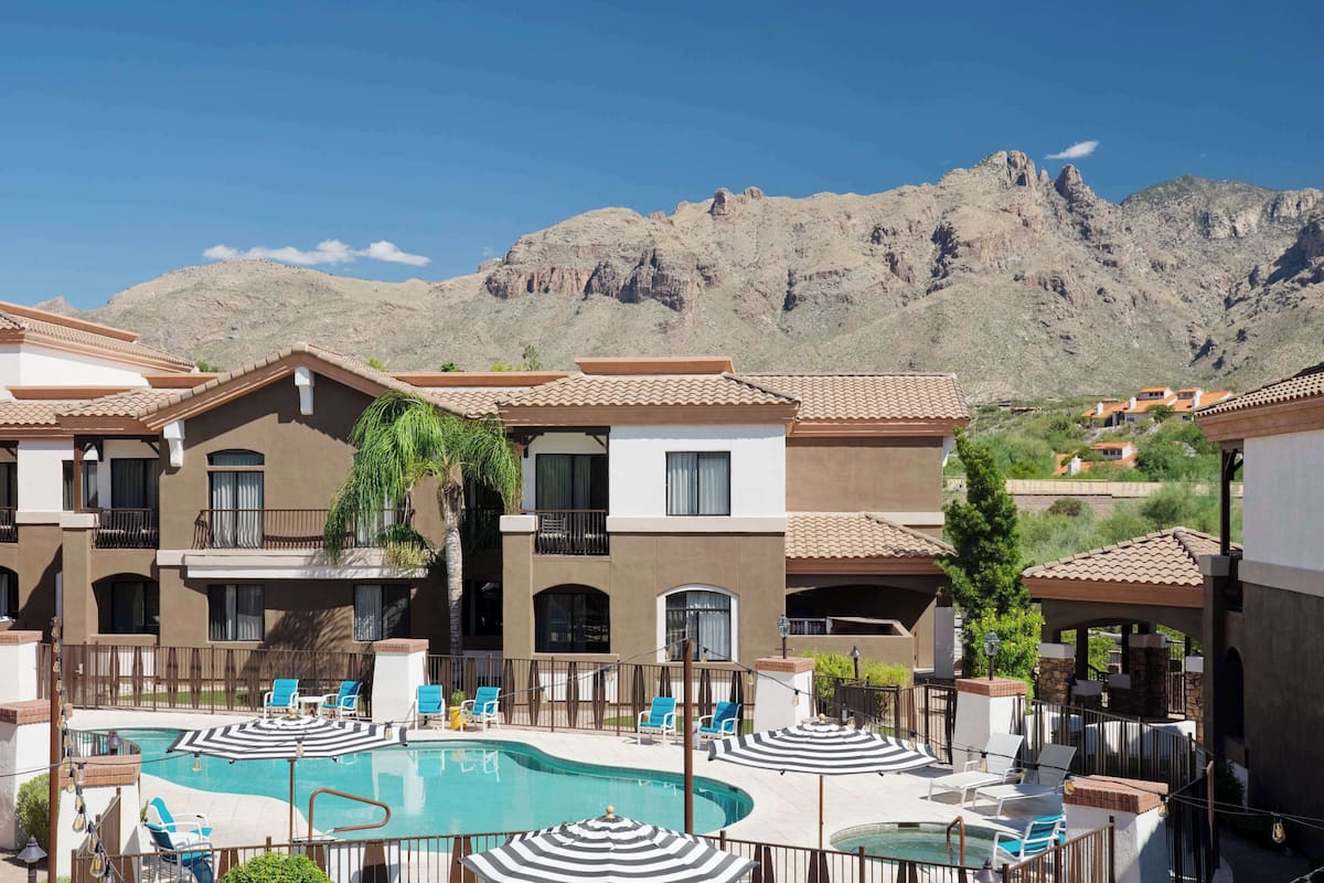 Un hôtel doté d’une piscine, de chaises longues et offrant une vue sur les montagnes.
