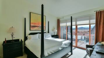 Ein Bett mit Baldachin und Blick auf die Stadt, ein Nachttisch mit Lampe und ein Fenster mit Jalousien.