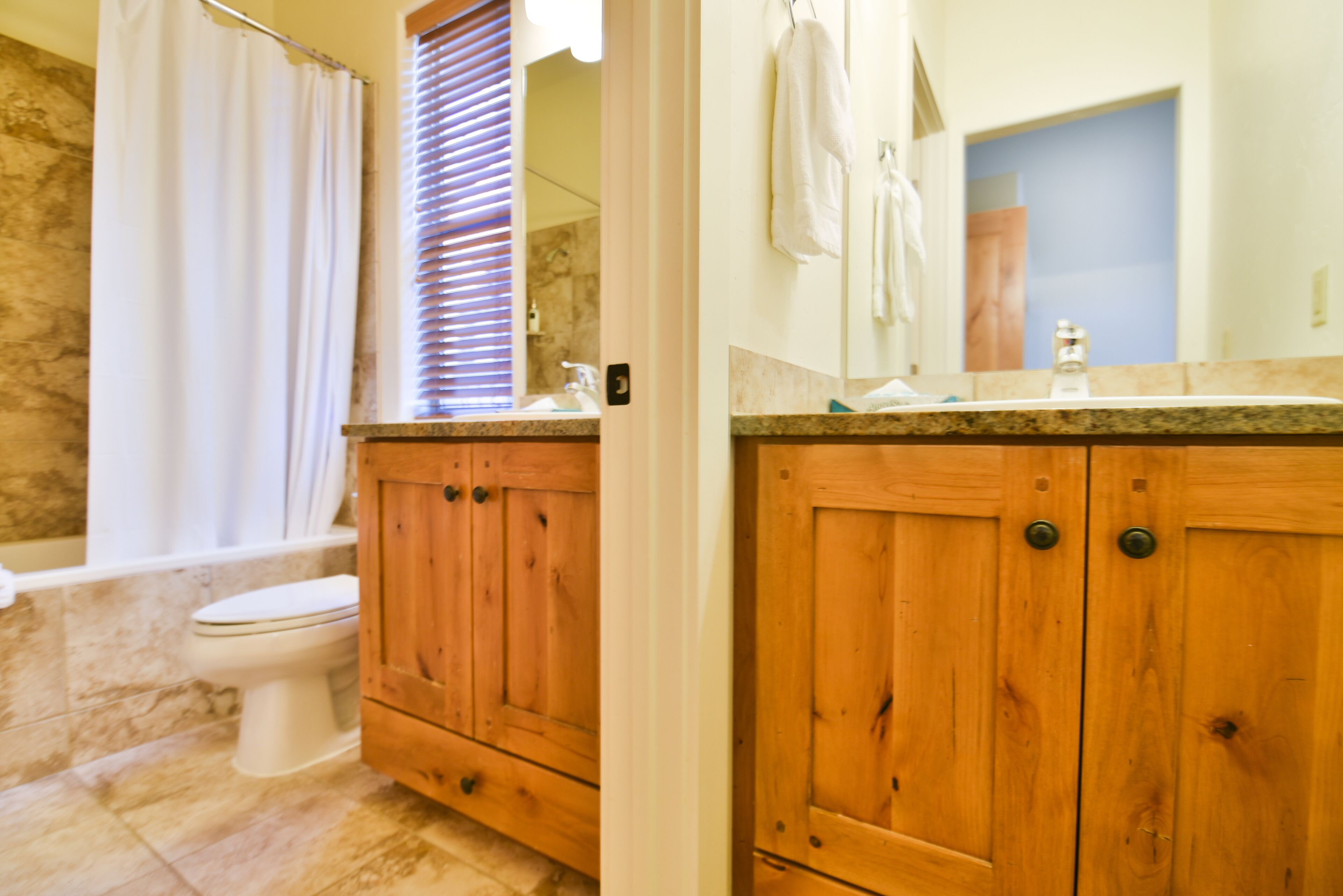 Un baño con armarios de madera, inodoro, lavamanos y espejo.
