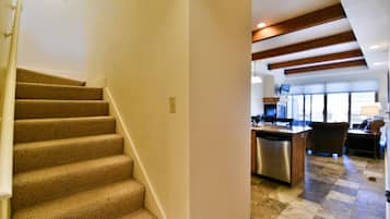 Una escalera conduce a una zona de cocina con lavavajillas y un comedor con mesa y sillas.