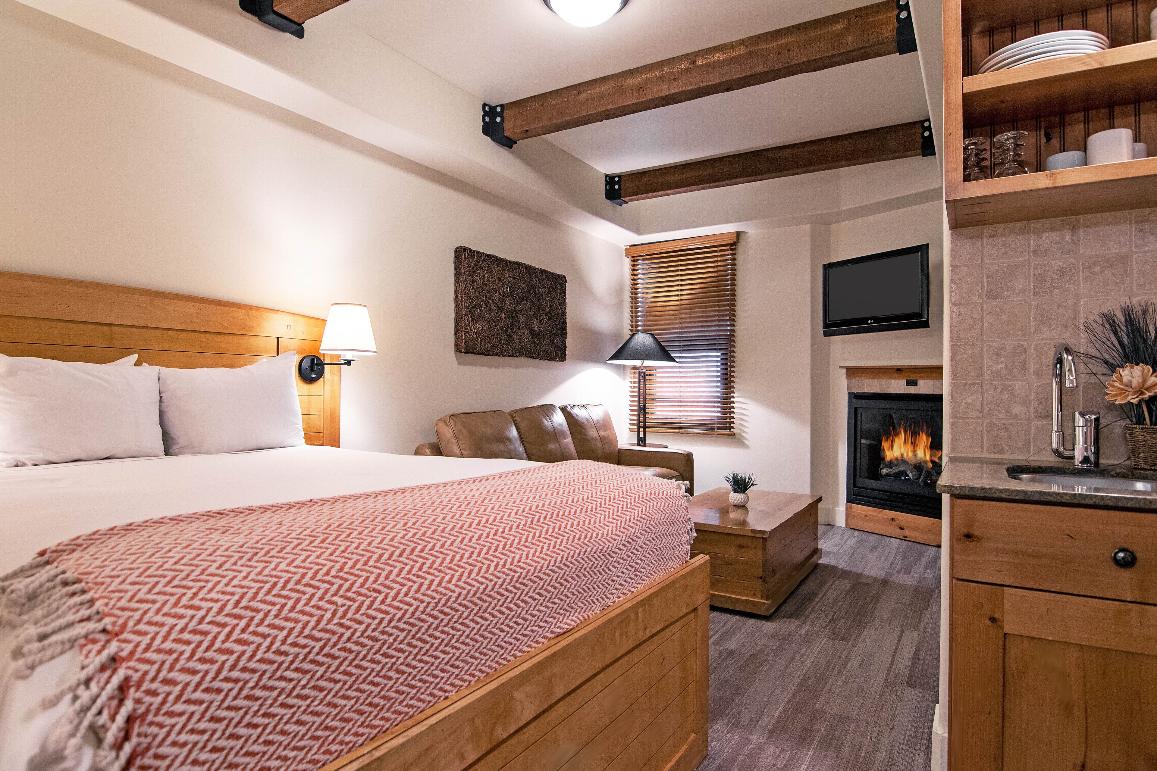 A bedroom with a bed, bedside table, lamp, and a fireplace.