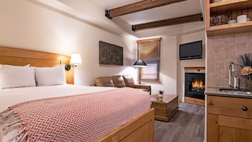A bedroom with a bed, bedside table, lamp, and a fireplace.