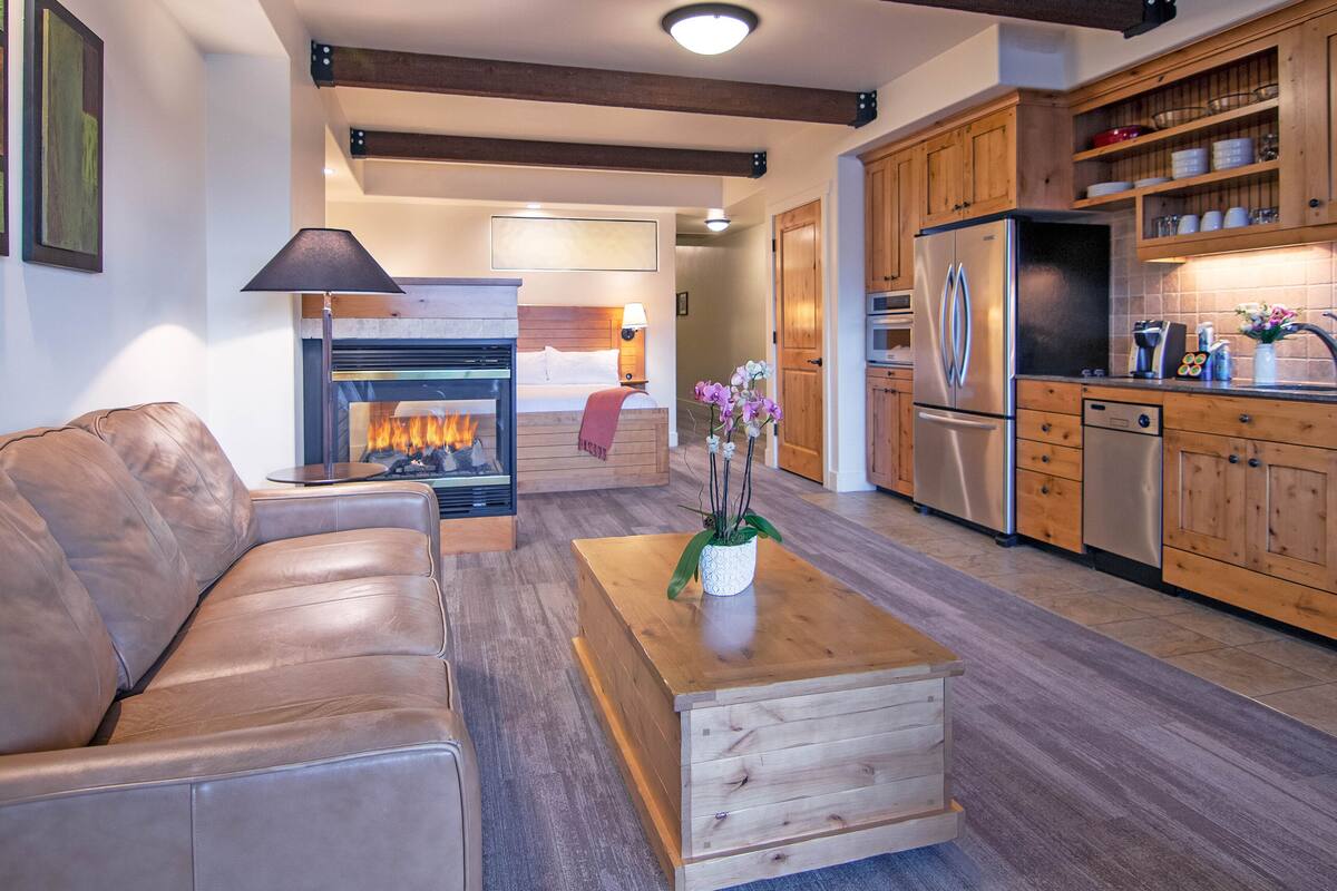 A modern living room with a leather sofa, a wooden coffee table, and a fireplace.