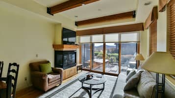 A spacious living room with a fireplace, large windows, and a comfortable seating area.