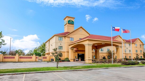 A hotel with a prominent clock tower, a red roof, and two flags. - La Quinta Inn & Suites by Wyndham Pasadena (Pasadena)