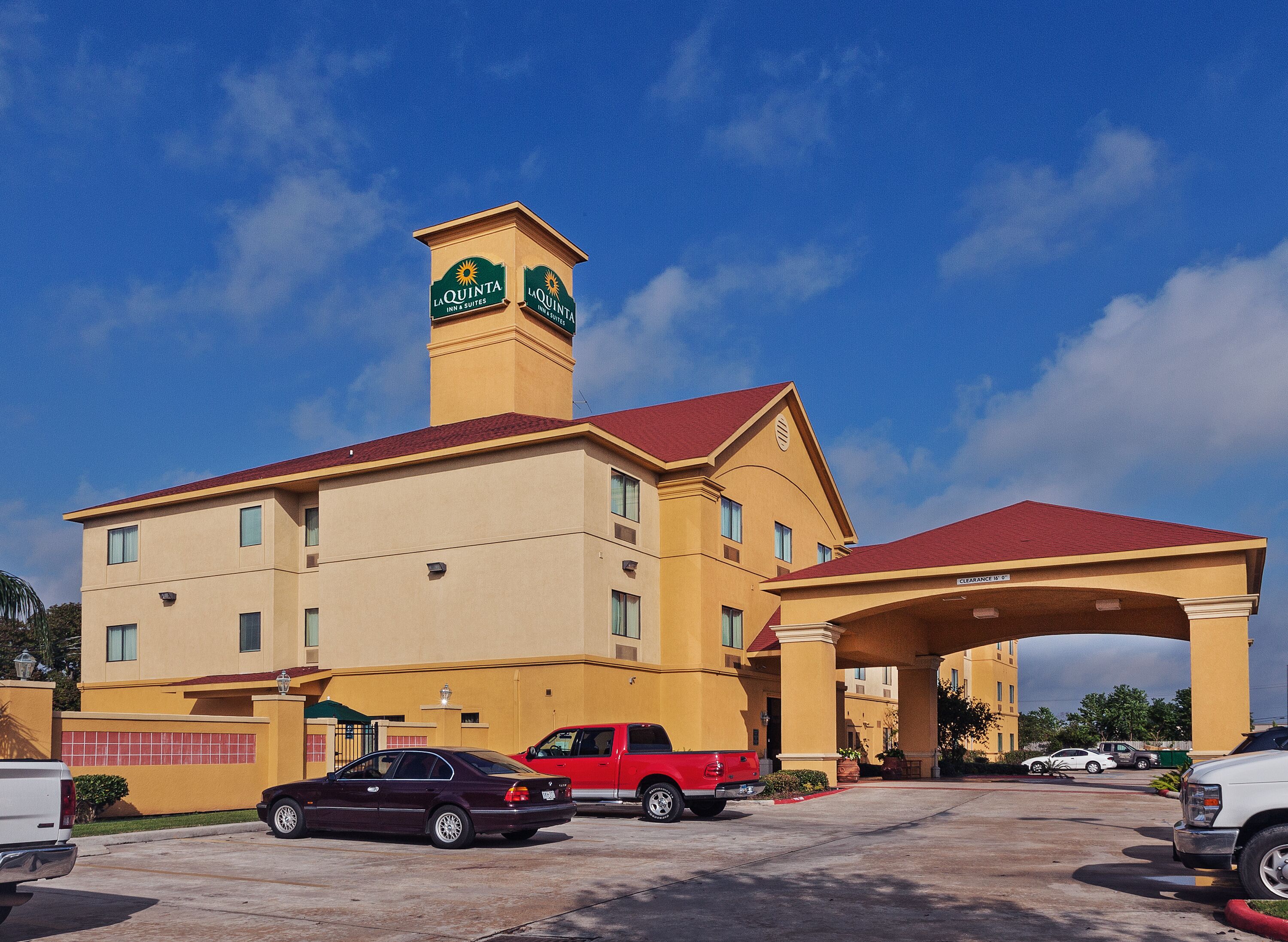 A hotel with a prominent tower, multiple balconies, and a covered parking area.