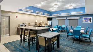 Un comedor de hotel con bar, varias mesas y sillas, e iluminación decorativa en el techo.