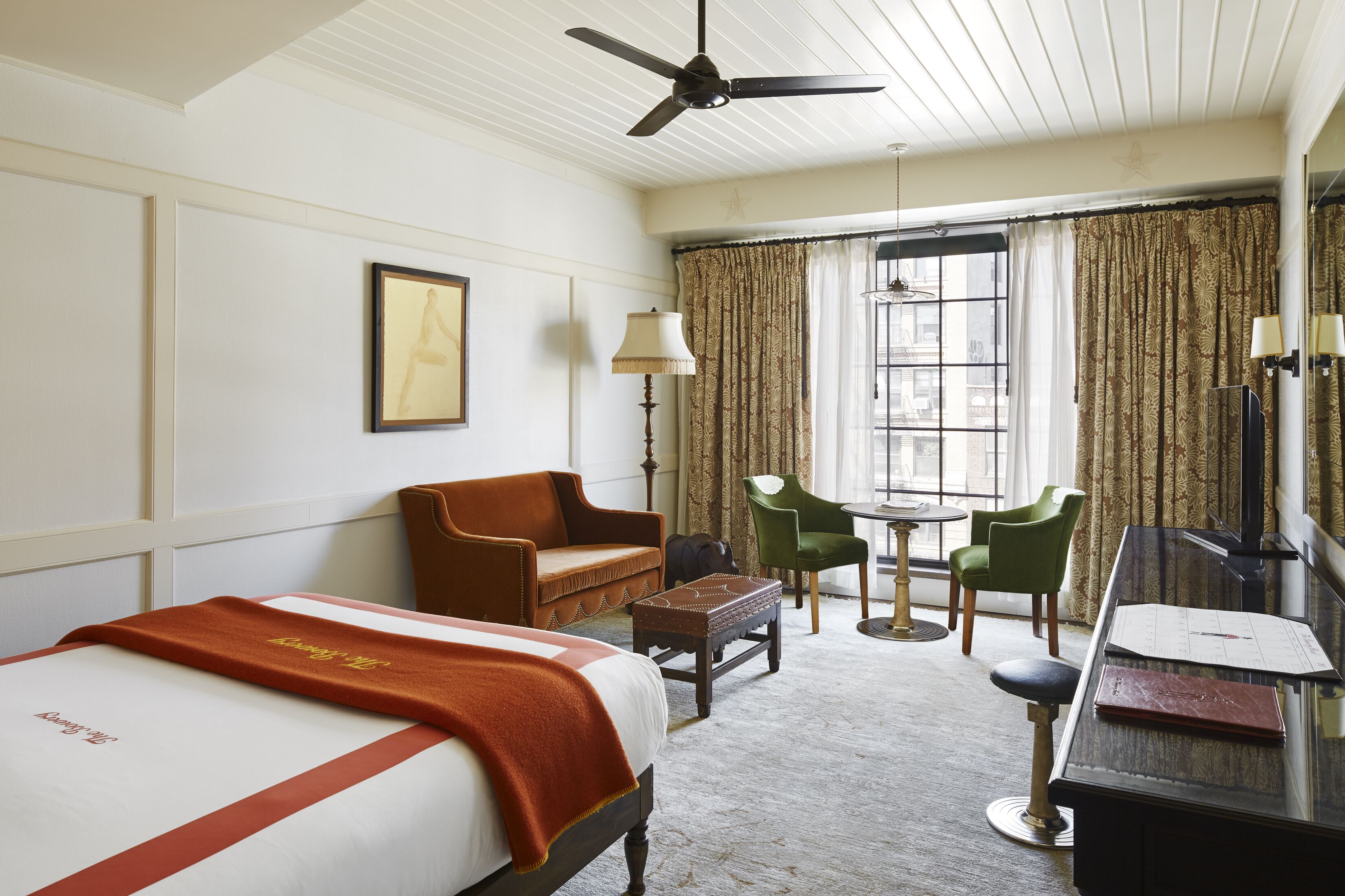 Una habitación de hotel con una cama, un escritorio, una silla, una mesita y una ventana con cortinas.