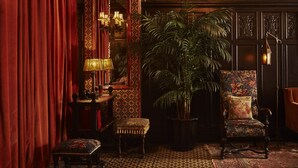 A richly decorated room with a large mirror, ornate lamps, a potted plant, and a patterned rug. - The Bowery Hotel (New York)