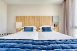 A hotel room with two beds, a wooden headboard, bedside lamps, a telephone, and a window with curtains. - Hôtel de Bellevue Gare du Nord (Paris)