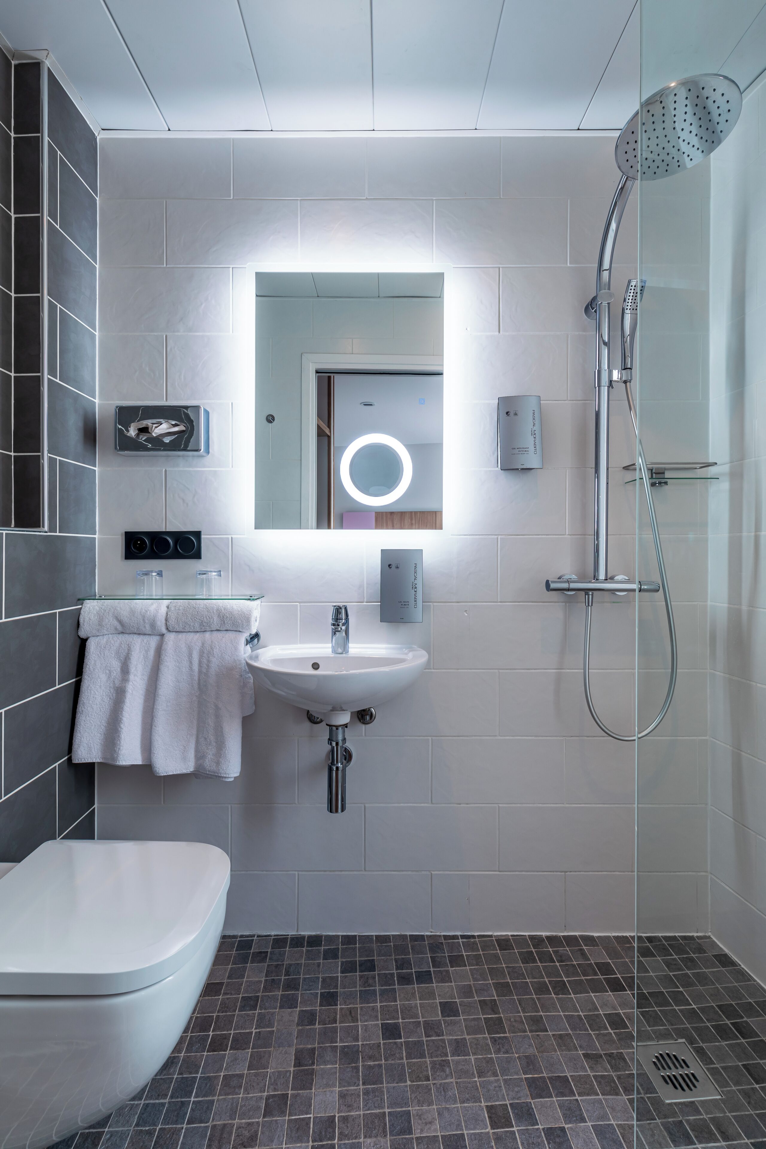 A modern bathroom with a toilet, sink, and shower.