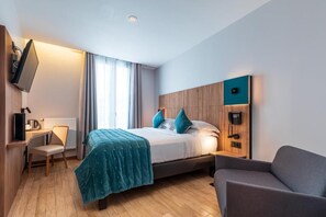 Una habitación de hotel moderna con cama, escritorio, silla, televisor y teléfono.