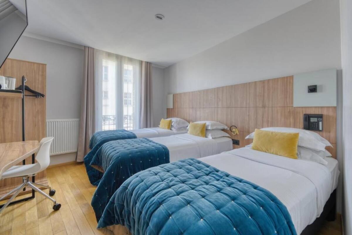 Habitación de hotel con dos camas, un escritorio y una silla.
