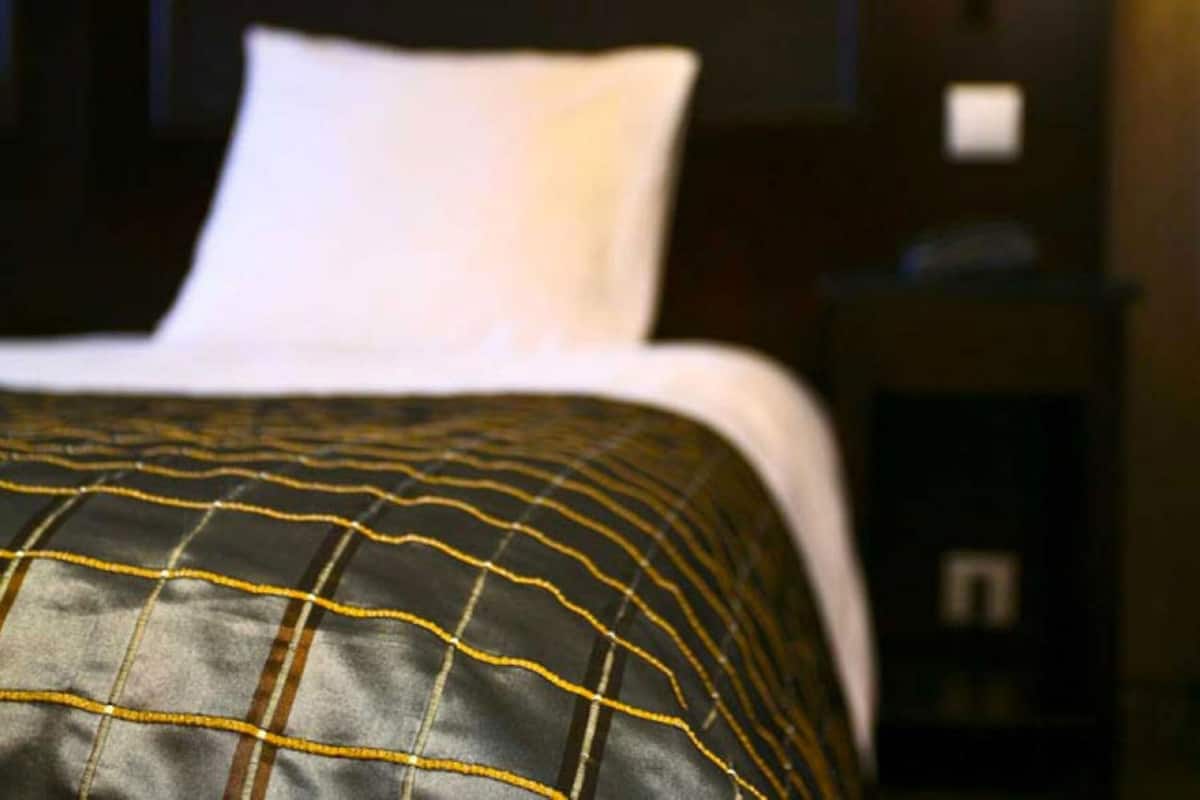 A bed with a black and white patterned bedspread and a white pillow.