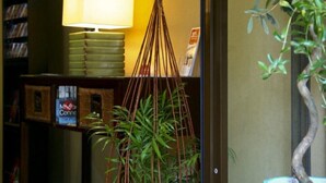 Una habitación con una planta colgante, una lámpara y una estantería con libros y un cartel.