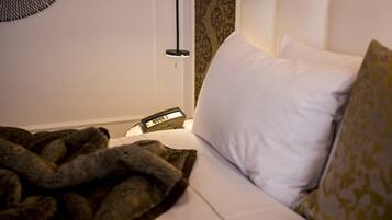 A neatly made bed with white and patterned pillows, a bedside table with a lamp, and a wall-mounted decorative item.