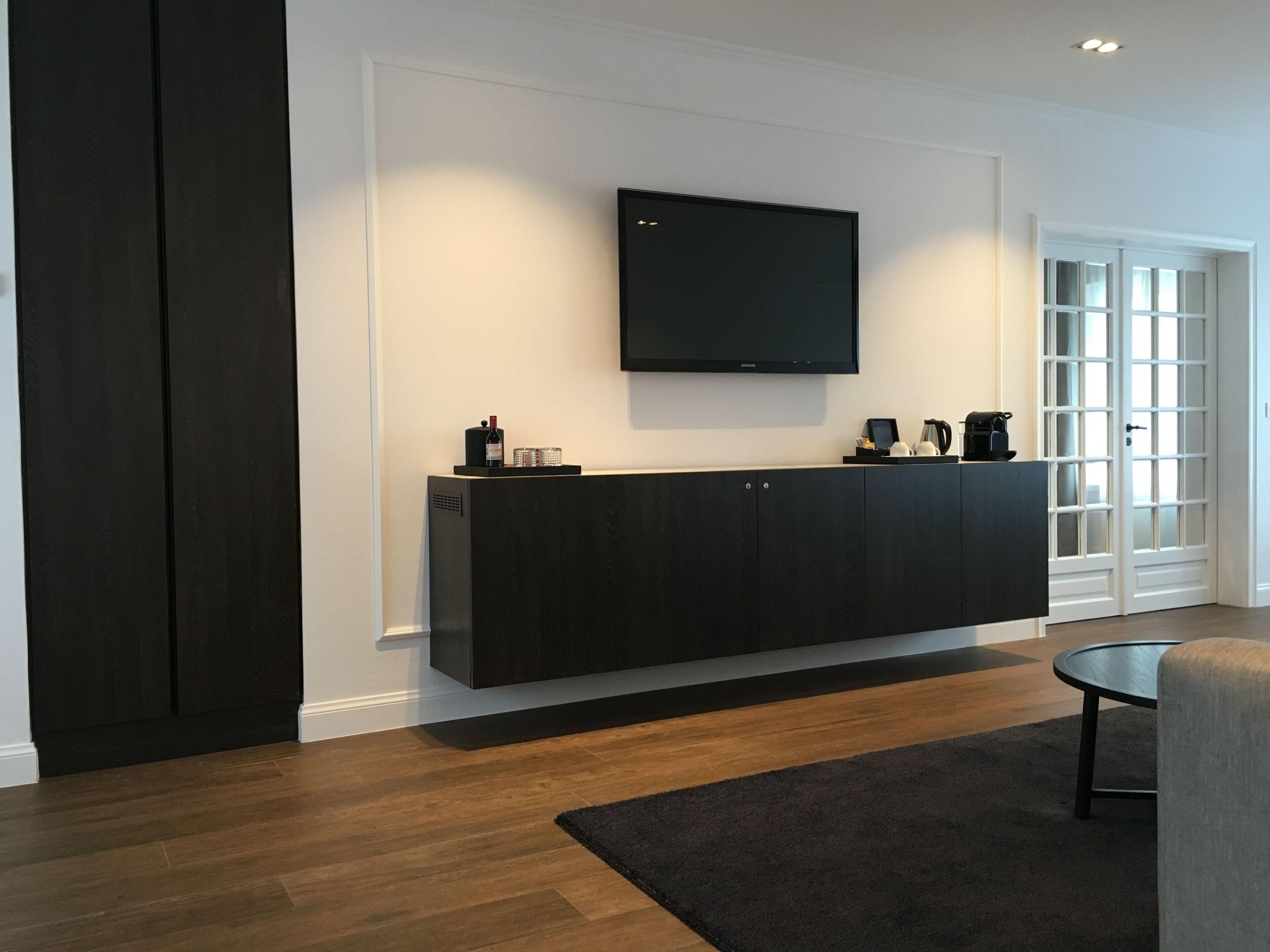 A modern living room with a dark wooden entertainment unit, a flat-screen TV mounted above it, and a round coffee table.