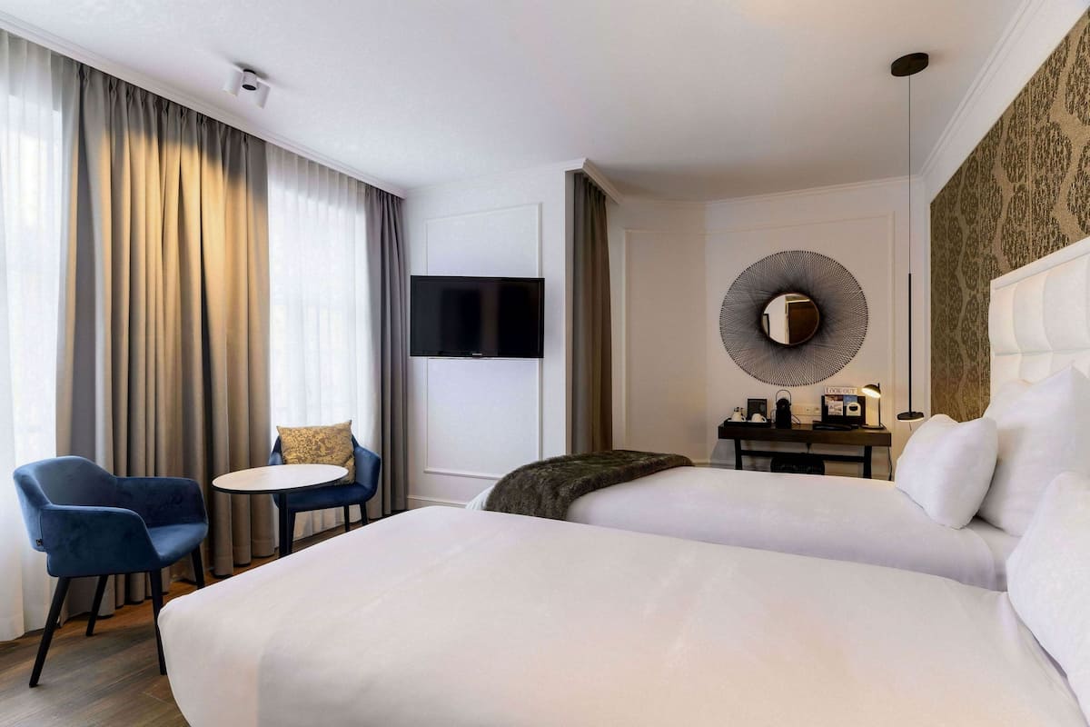Een hotelkamer met twee bedden, een televisie, een bureau met lamp en een stoel.