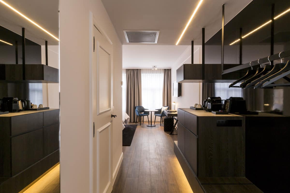 Een moderne keuken met donkere kastjes, een centraal eiland en een eetgedeelte met een tafel en stoelen.