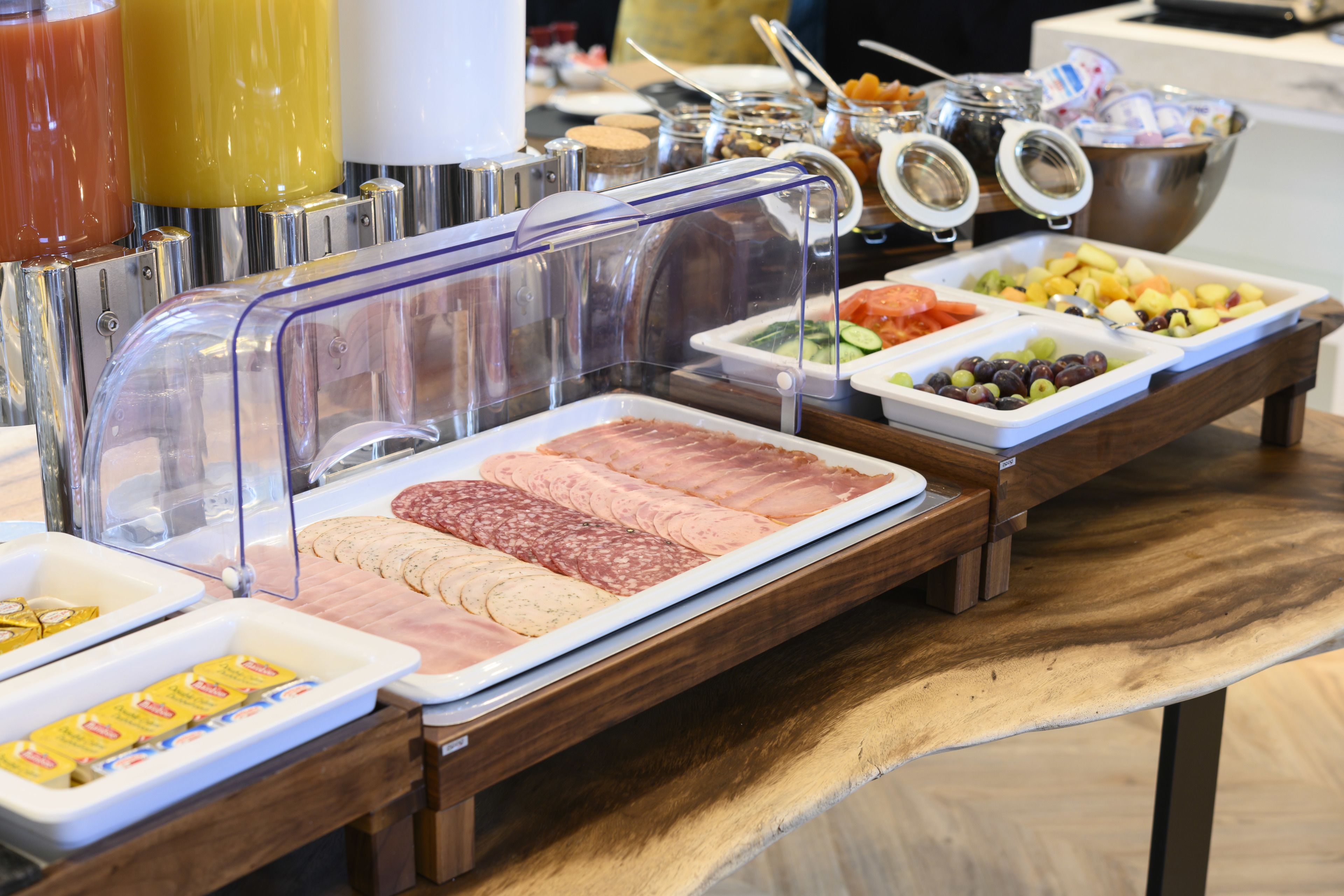 Un bufé con diversas opciones de comida, incluyendo carnes, quesos y frutas.