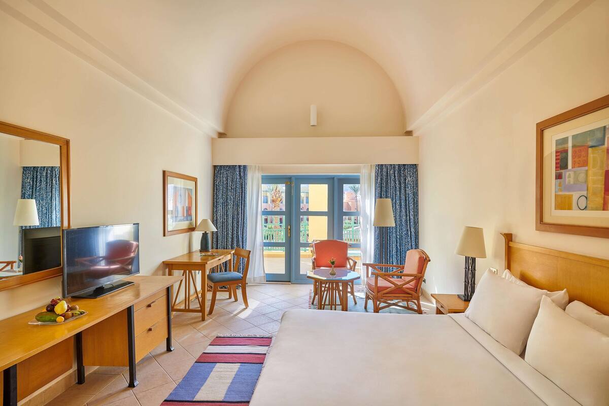 Habitación de hotel con cama, escritorio, televisión y zona de estar.