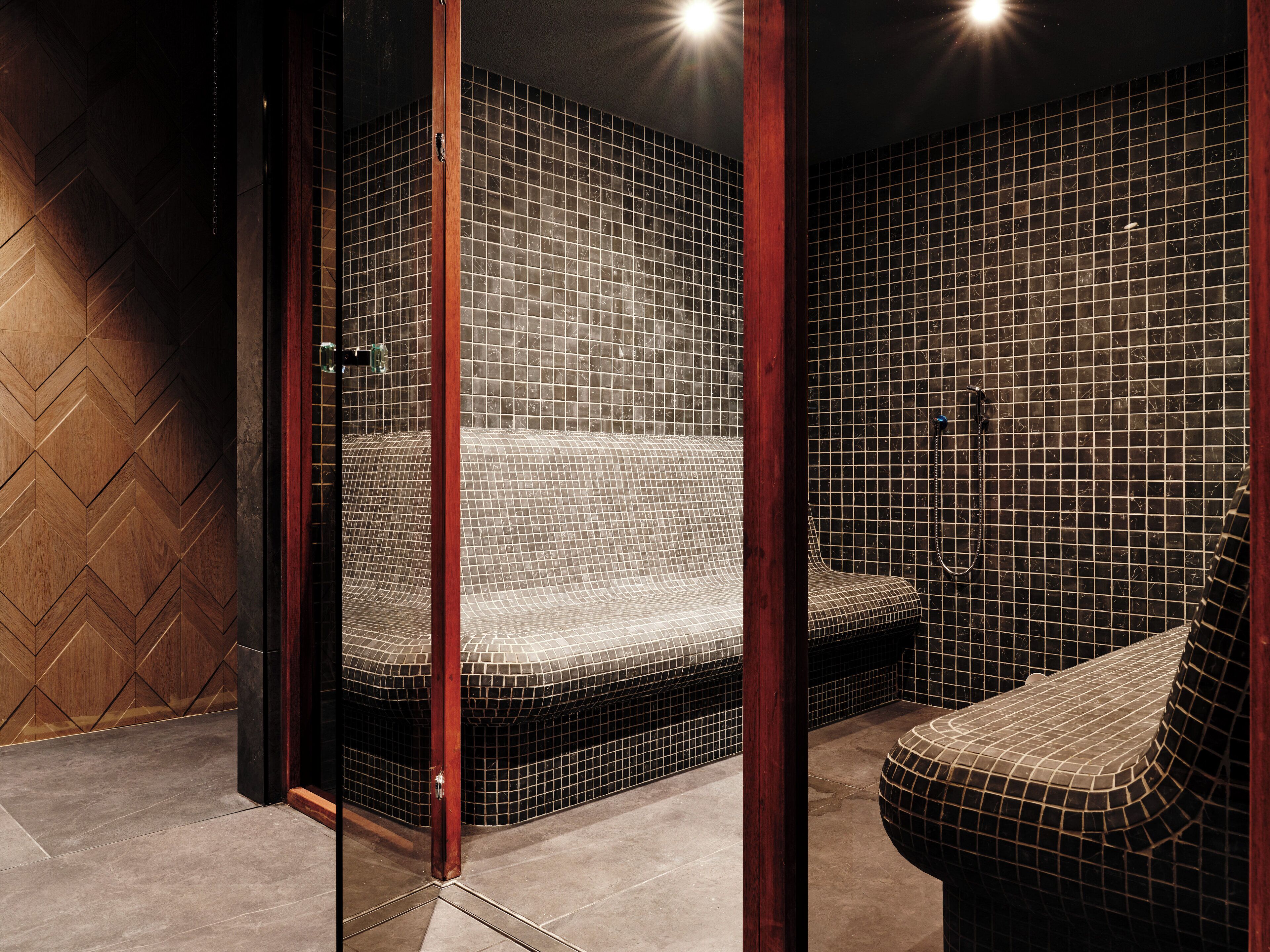 A modern bathroom with a large bathtub, a separate shower area, and a wooden accent wall.