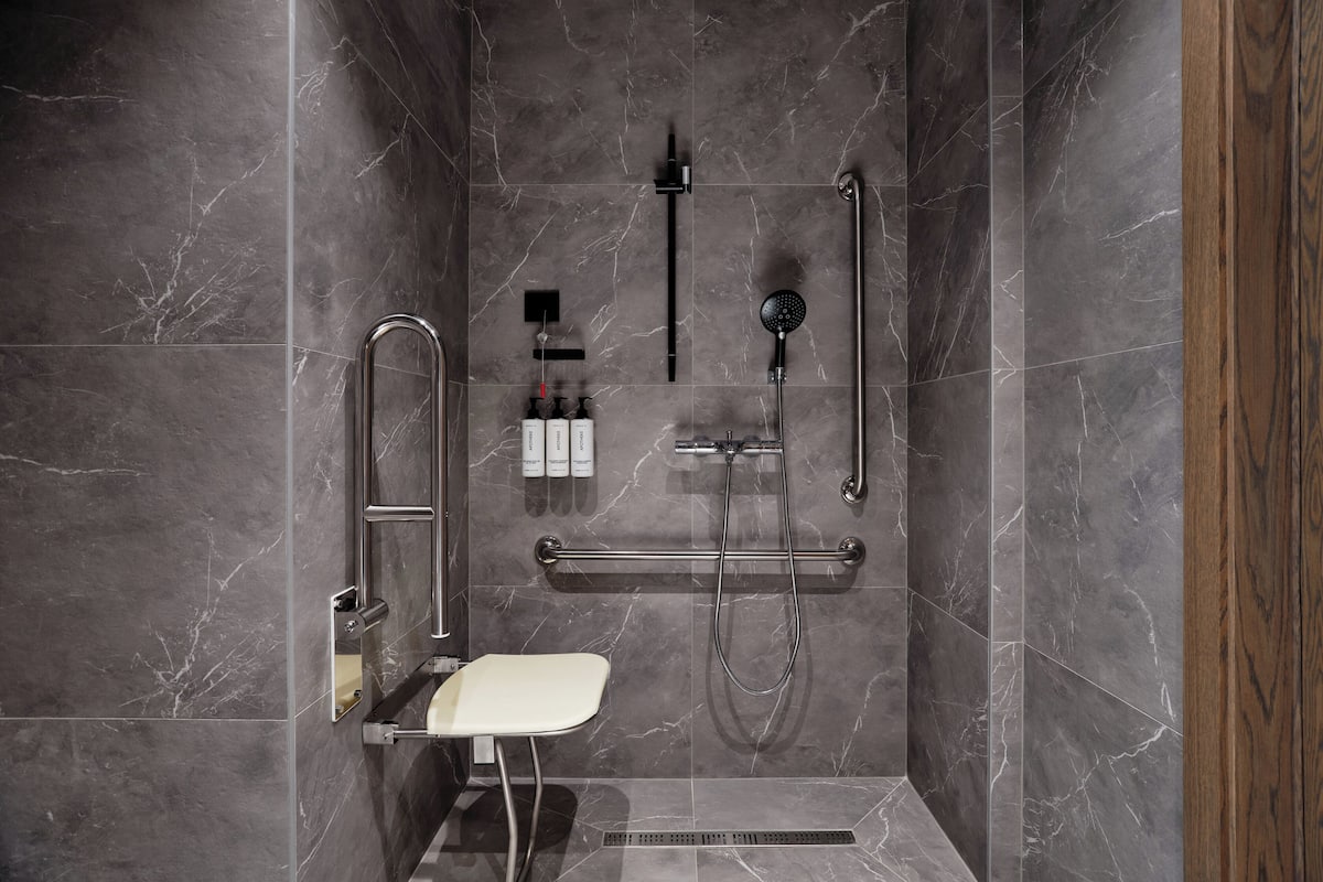 A modern shower area with a built-in seat, handheld showerhead, and a handheld shower attachment.