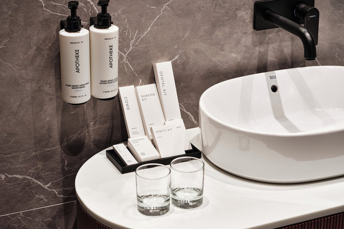 A bathroom with a white sink, two bottles of lotion, a comb, a shaving kit, and a shower cap.