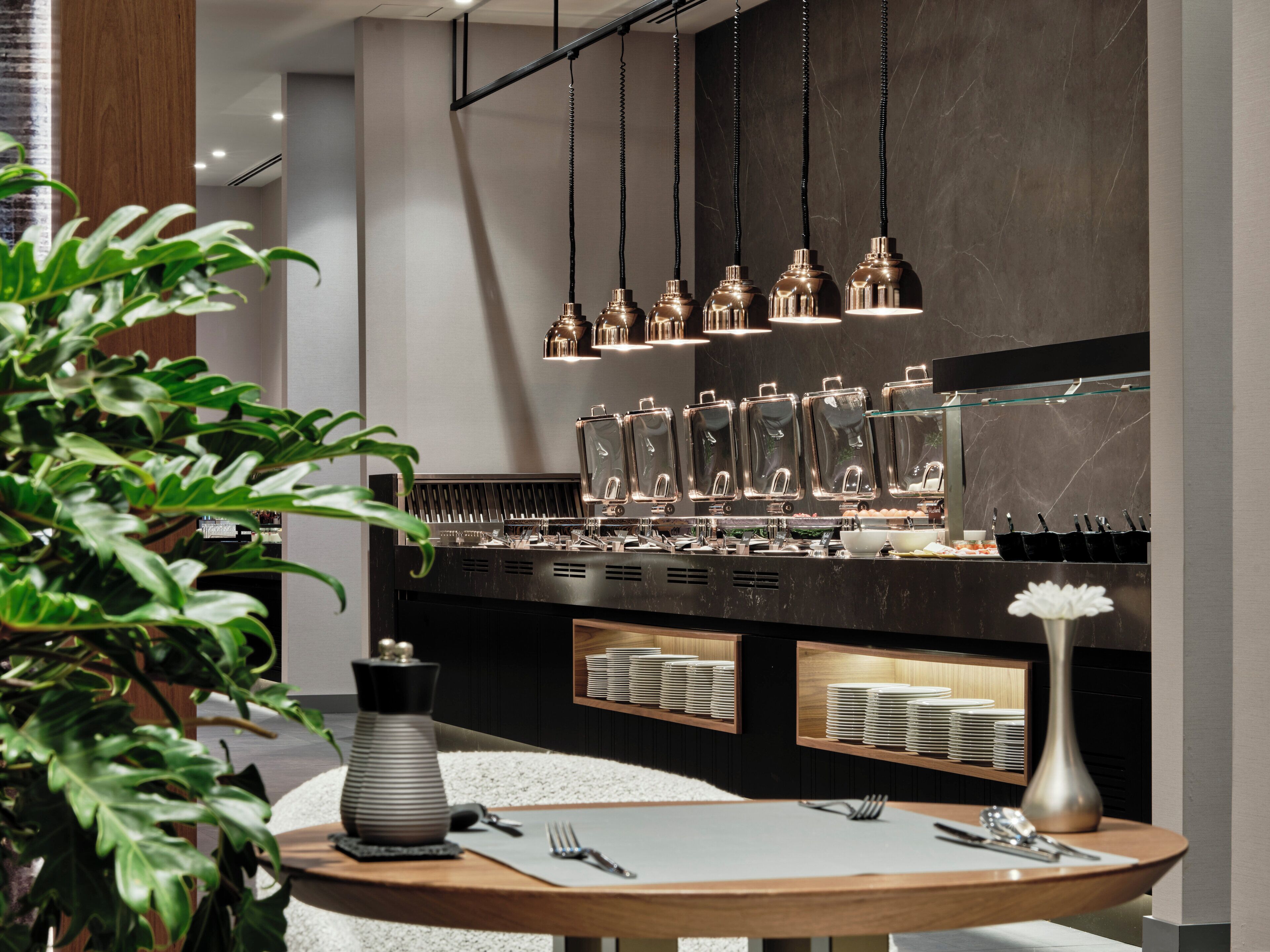 A modern buffet setup with clear glass containers, a central serving area, and a dining table with utensils.
