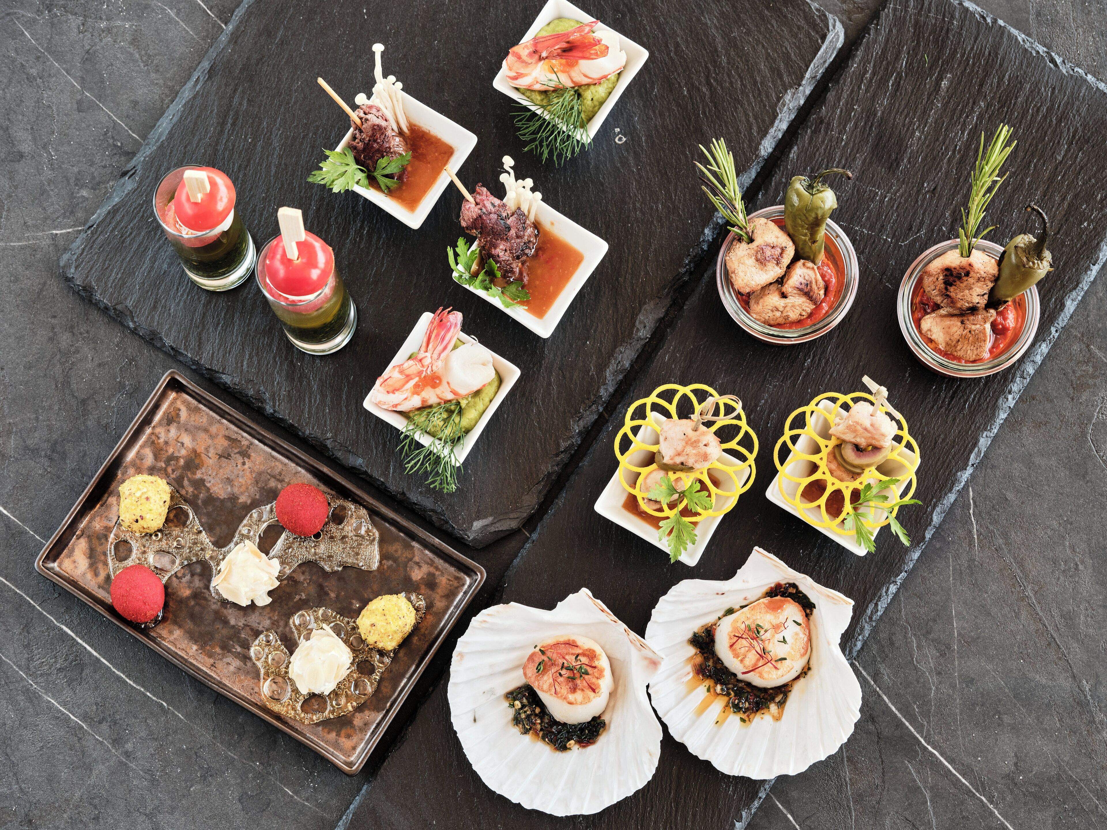 A variety of seafood dishes arranged on a slate table.
