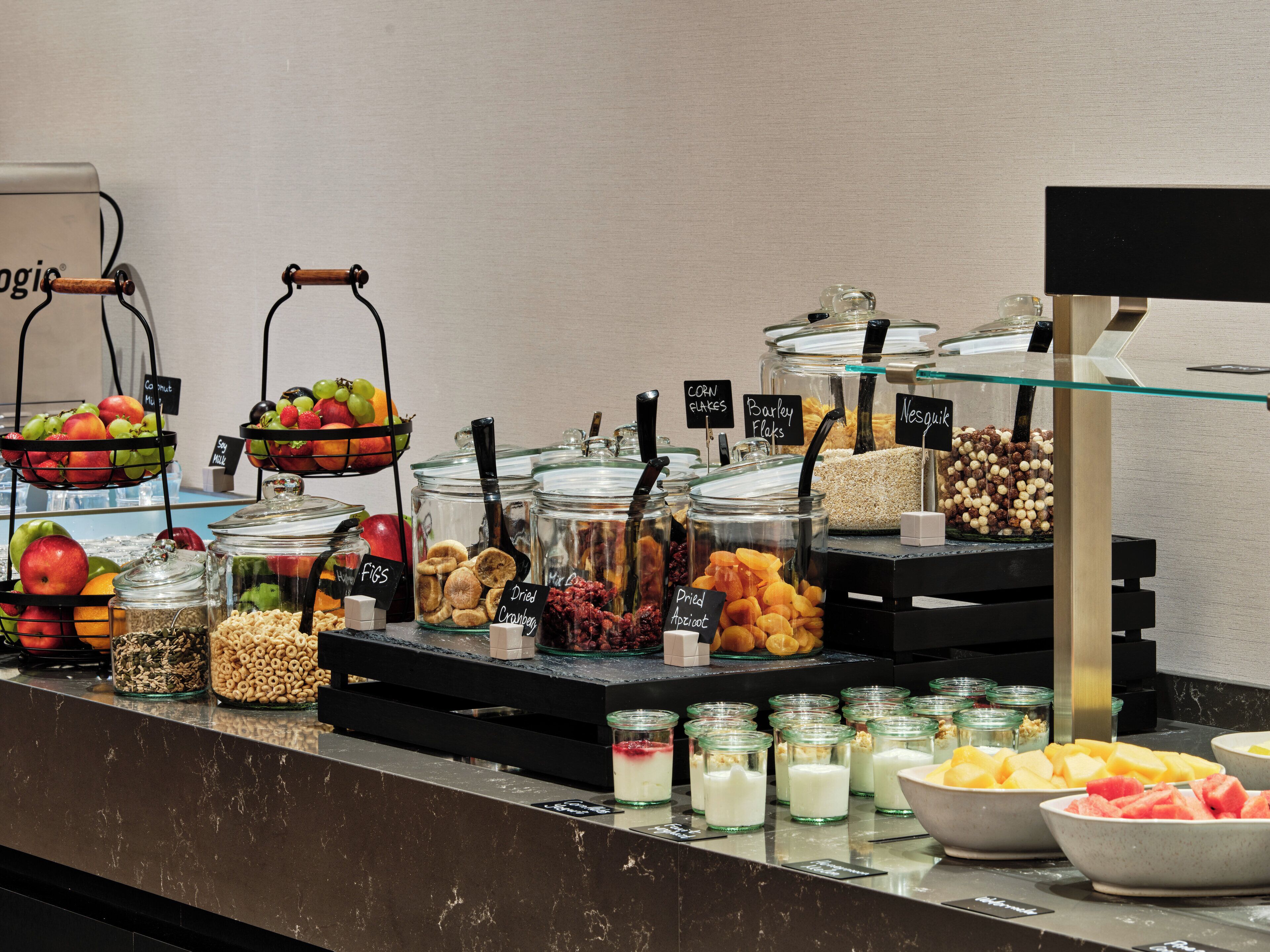 A buffet with various food items including fruits, cereals, and dairy products.