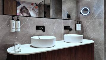A modern bathroom with two sinks, a mirror, and a ring light.