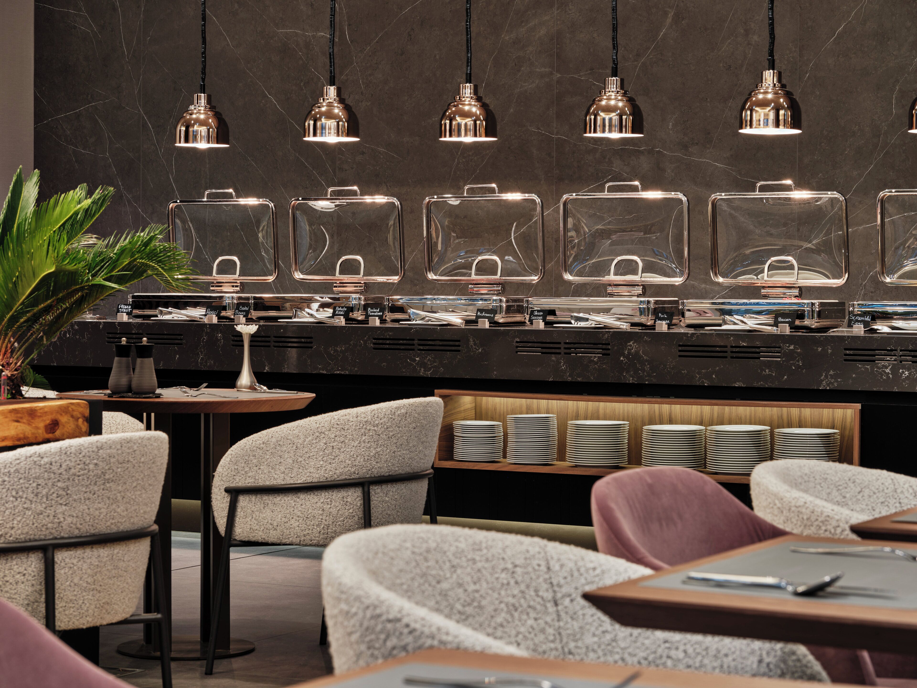 A modern cafe with a marble counter, clear glass containers, and multiple seating areas.