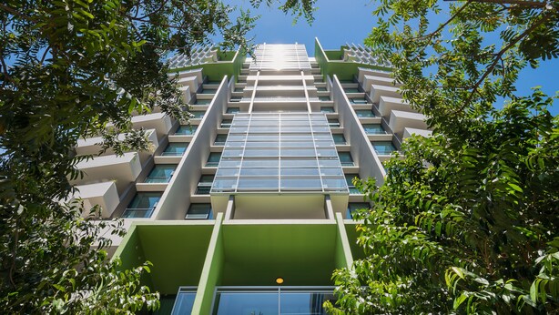 A modern high-rise building with a symmetrical facade, large windows, and green accents. - SKD SUITES (Spring Hill)