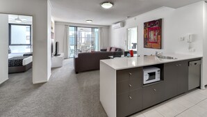 A modern apartment with a kitchen, dining area, and a balcony with a city view. - SKD SUITES (Spring Hill)