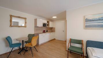 A compact living space with a kitchenette, a dining area with two chairs, and a bed.