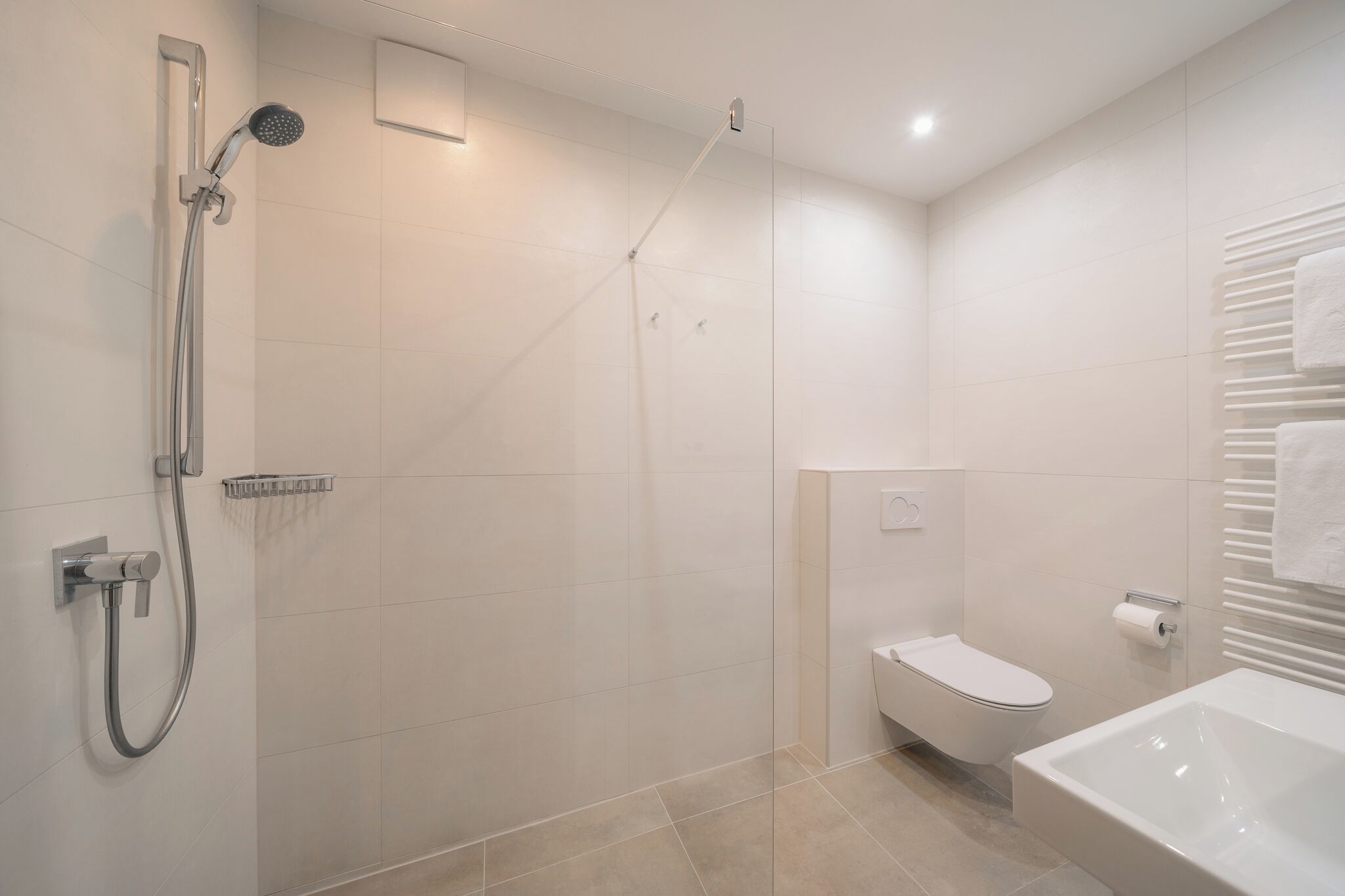 A modern bathroom with a glass-enclosed shower, a toilet, and a bathtub.