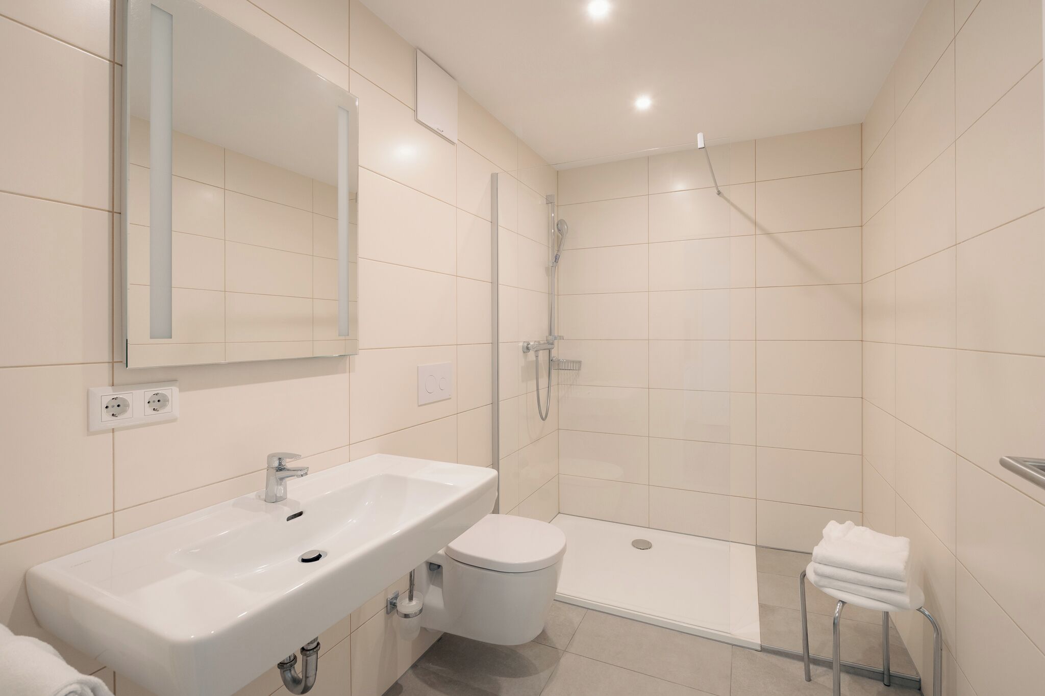 A modern bathroom with a sink, toilet, and shower.