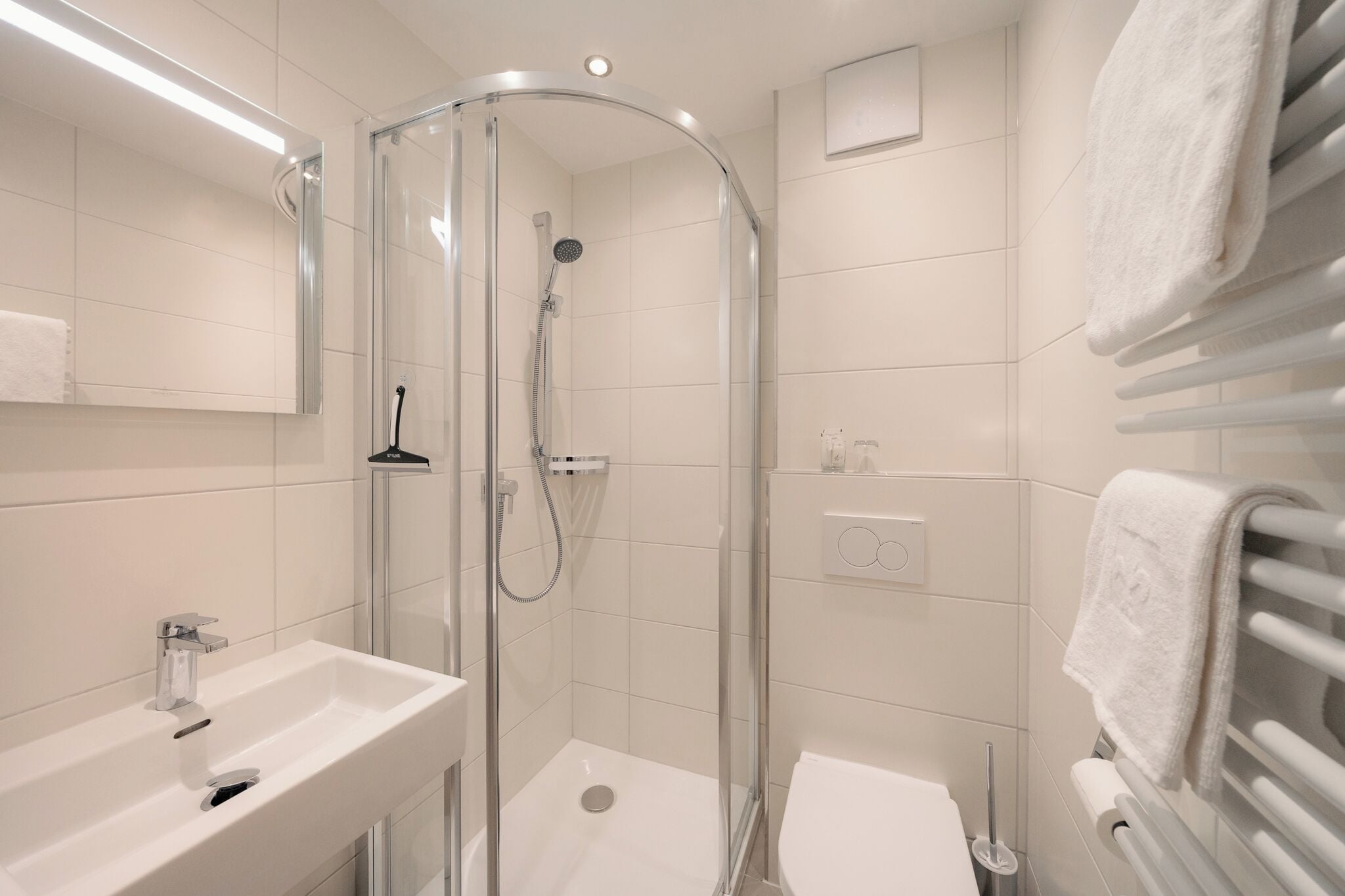 A modern bathroom with a glass-enclosed shower, a white sink, and a towel rack.