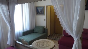 Une chambre à coucher comprenant un lit, un canapé, une petite table ronde et une armoire.
