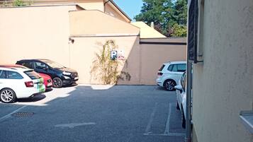 A parking area with several cars, a building with a beige facade, and a clear blue sky.