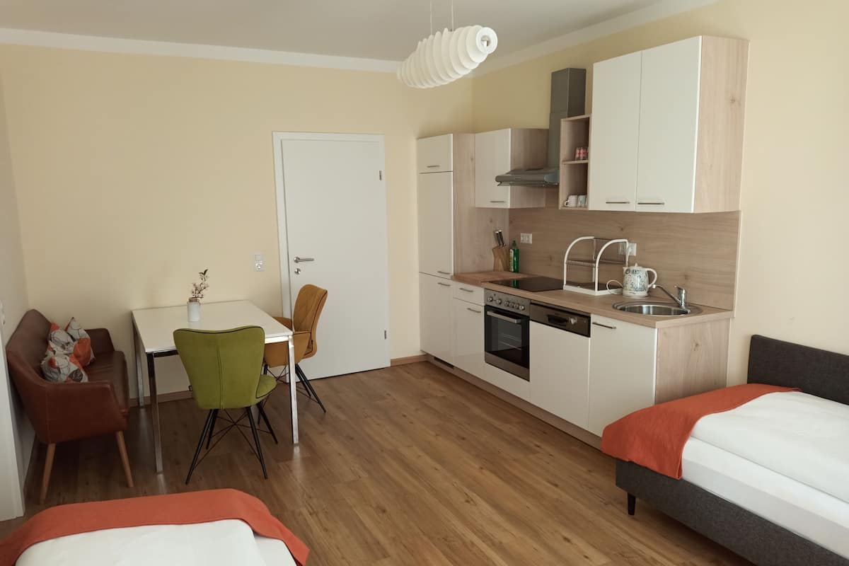 Ein kleines Hotelzimmer mit Küchenzeile, Essbereich und zwei Betten.