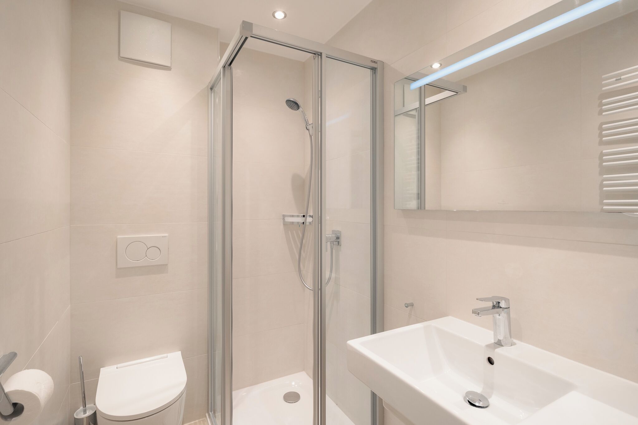 A modern bathroom with a glass-enclosed shower, a white sink, and a toilet.