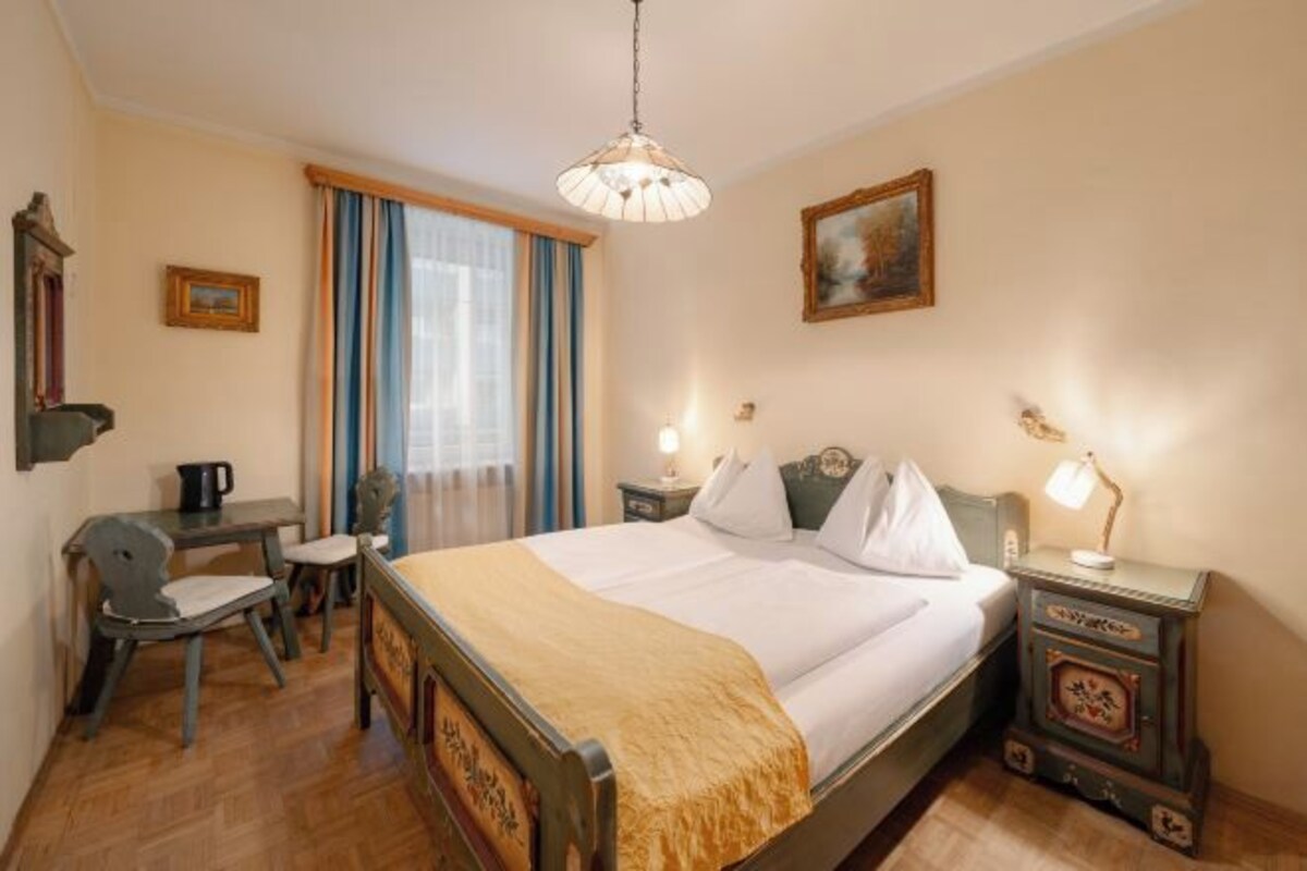 Une chambre d’hôtel avec un lit, un bureau, une chaise et une fenêtre avec des rideaux.